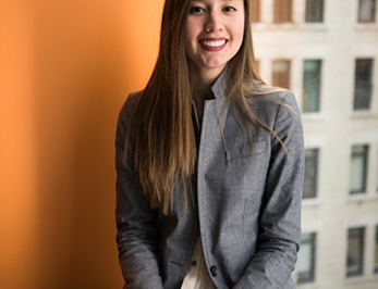 Young woman in a suit with long, straight hair smiling